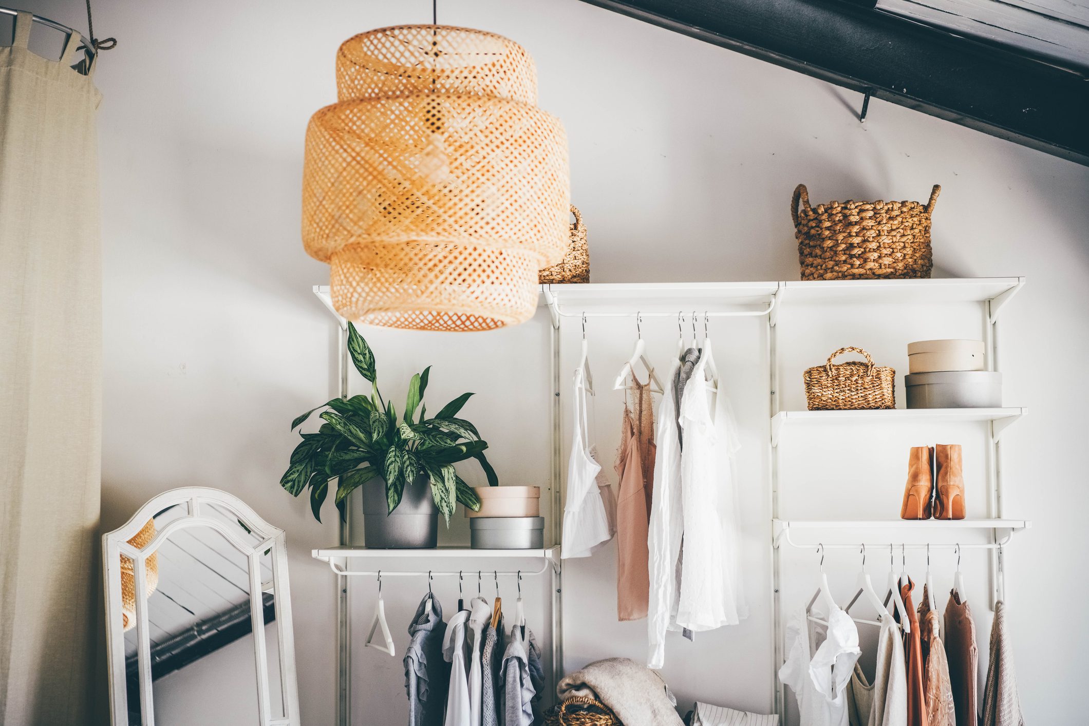 Stylish closet with clothes and wicker baskets.