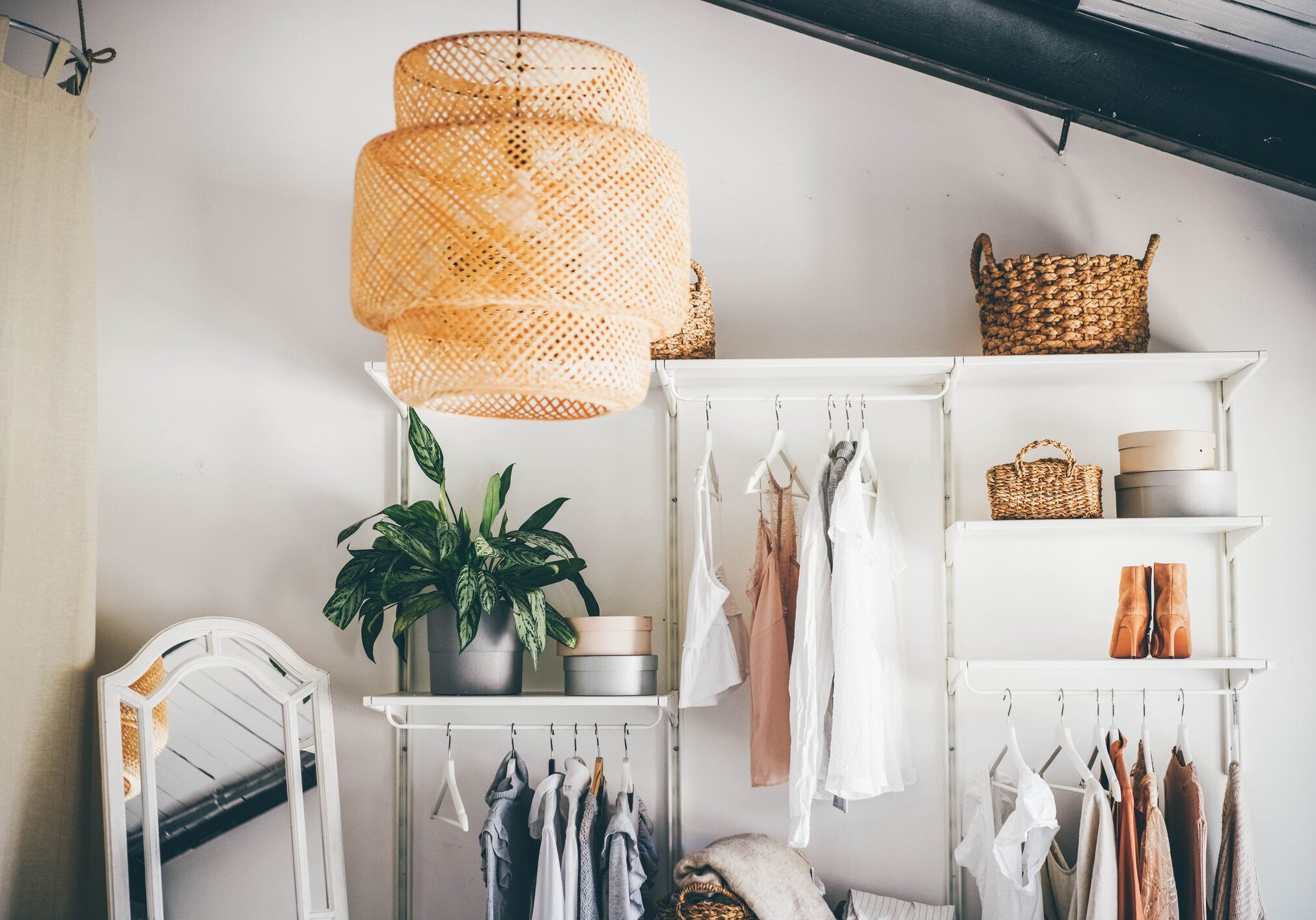 Stylish closet with clothes and wicker baskets.